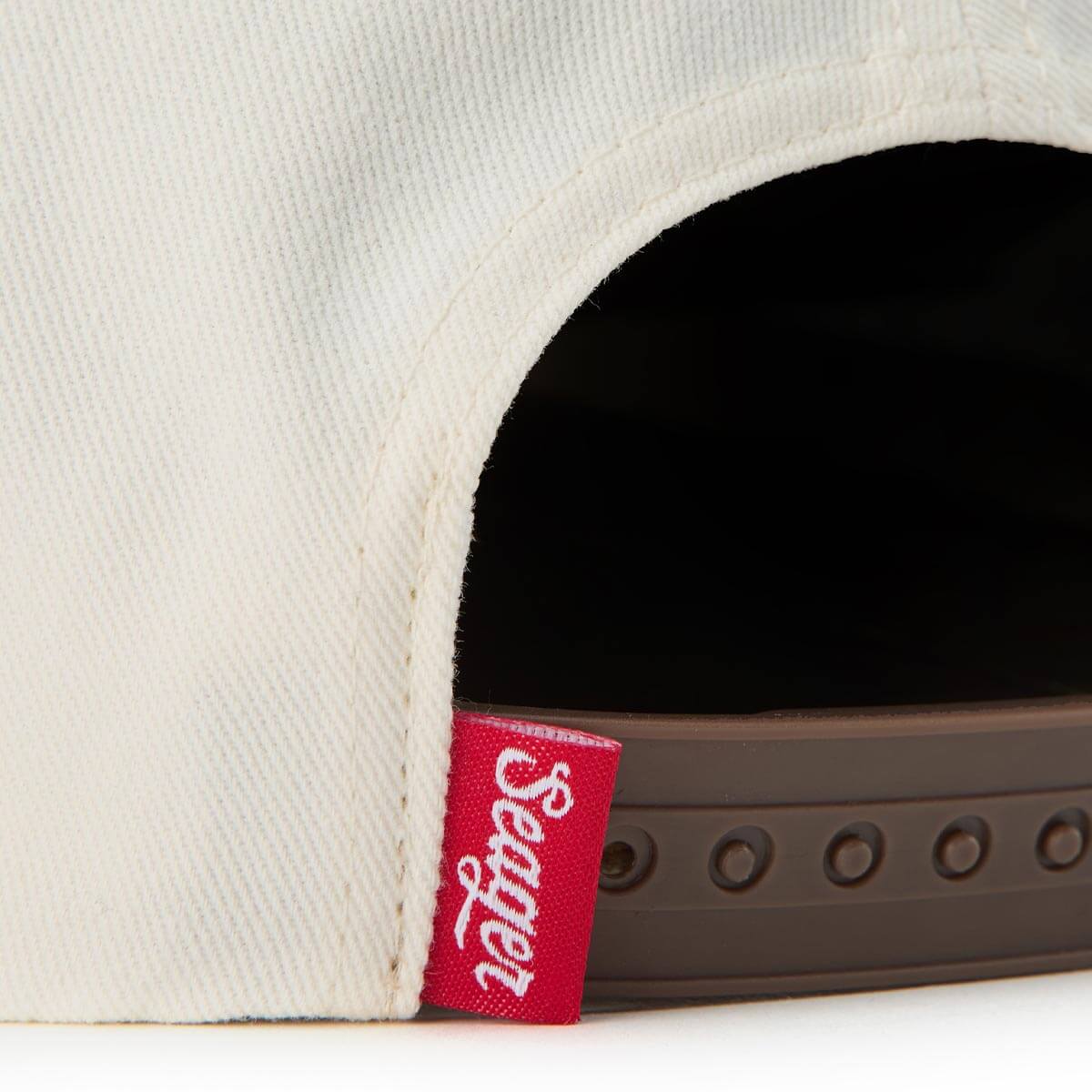 Close-up of a cap with a red Sealer logo tag on a white background