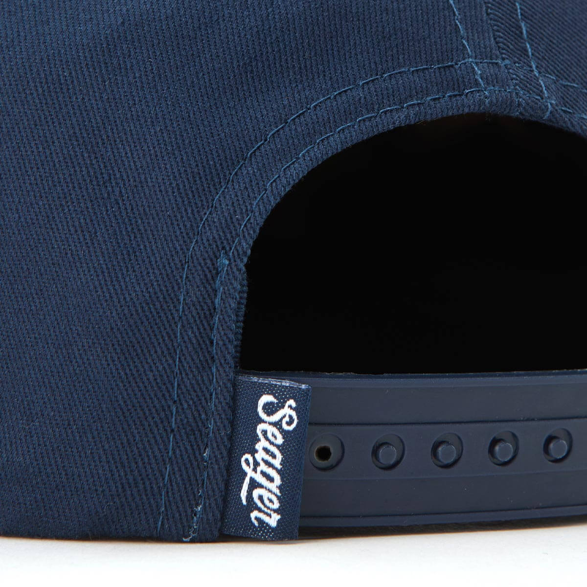 Navy blue cap with a brand logo on the strap against a white background