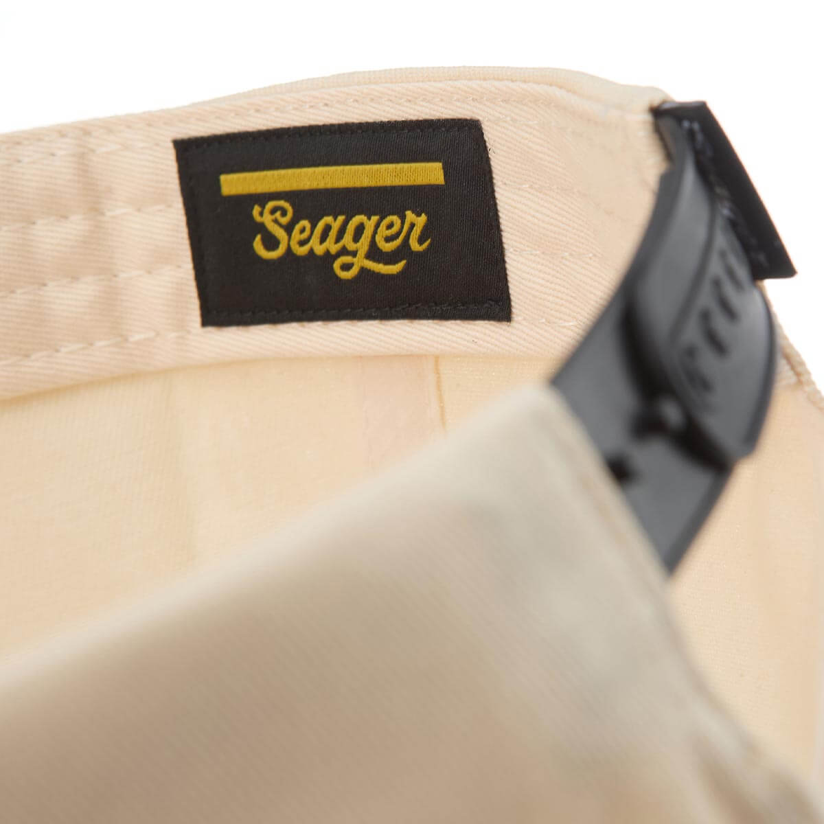 Beige cap with a black 'Seager' logo tag on a white background